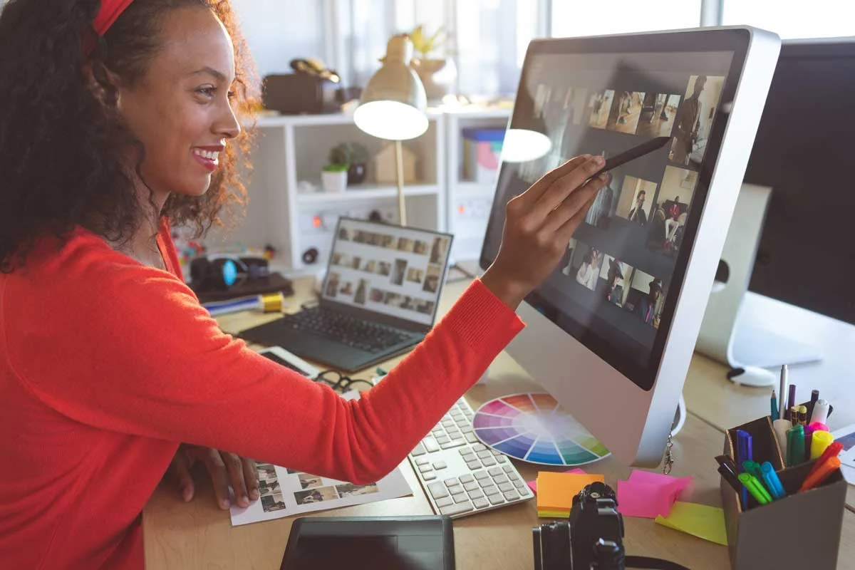 Tauche ein in die Welt der Fotoausarbeitung. Frau die an einem PC sitzt und Fotos bearbeitet